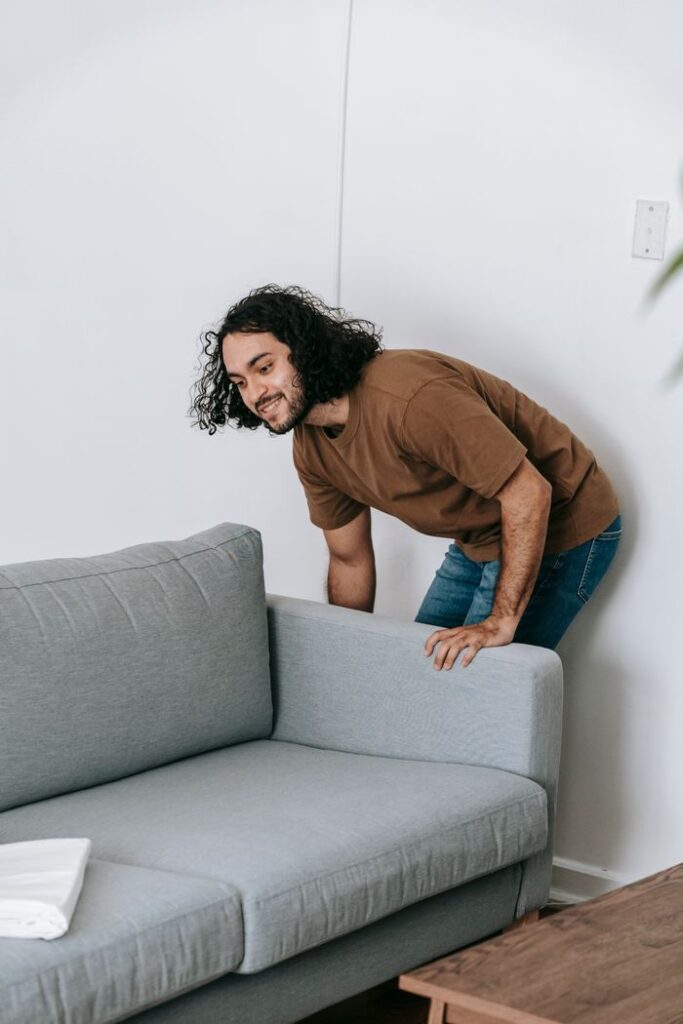 The Art of Drawing Readers In: Your attractive post title goes here Man with curly hair arranging a grey sofa in a contemporary living room.